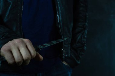 Genç adam bir bıçak ile yaklaşık saldırı, koyu arka plan üzerinde.