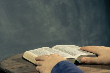 Kutsal İncil okuma bir masada oturan genç adam