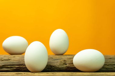 Eski bir meşe ahşap masa turuncu arka plan üzerinde yumurta.