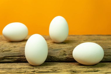 Eski bir meşe ahşap masa turuncu arka plan üzerinde yumurta.