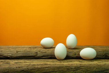Eski bir meşe ahşap masa turuncu arka plan üzerinde yumurta.