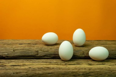 Eski bir meşe ahşap masa turuncu arka plan üzerinde yumurta.