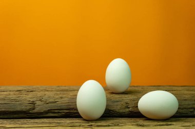 Eski bir meşe ahşap masa turuncu arka plan üzerinde yumurta.