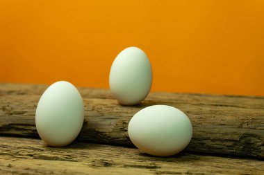 Eski bir meşe ahşap masa turuncu arka plan üzerinde yumurta.