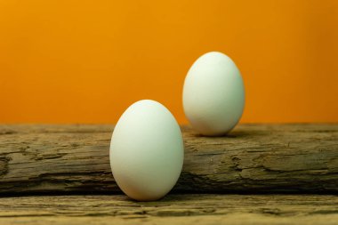 Eski bir meşe ahşap masa turuncu arka plan üzerinde yumurta.