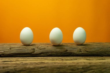 Eski bir meşe ahşap masa turuncu arka plan üzerinde yumurta.