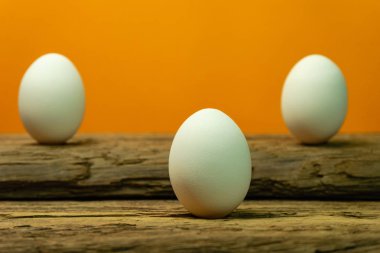 Eski bir meşe ahşap masa turuncu arka plan üzerinde yumurta.