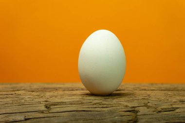 Eski bir meşe ahşap masa turuncu arka plan üzerinde yumurta.