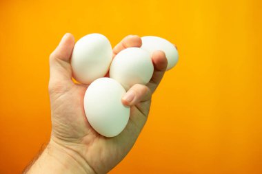 Yumurta turuncu bir arka plan üzerinde tutan el.