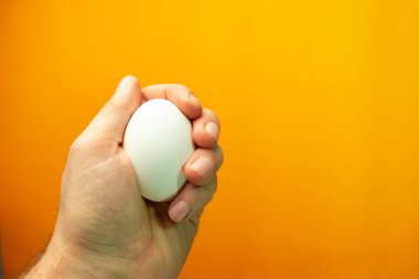 Yumurta turuncu bir arka plan üzerinde tutan el.