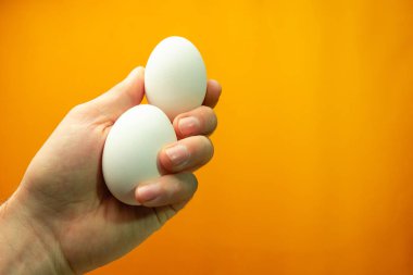 Yumurta turuncu bir arka plan üzerinde tutan el.
