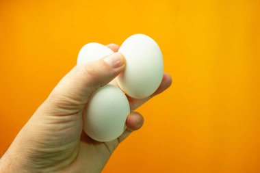 Yumurta turuncu bir arka plan üzerinde tutan el.