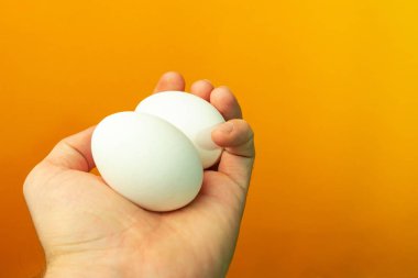 Yumurta turuncu bir arka plan üzerinde tutan el.
