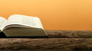 Kutsal İncil'in eski meşe ahşap bir masa üzerine. Güzel turuncu arka plan. Din kavramı.