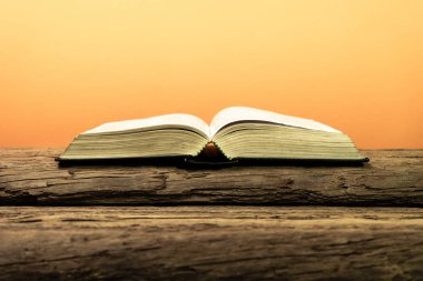 Kutsal İncil'in eski meşe ahşap bir masa üzerine. Güzel turuncu arka plan. Din kavramı.