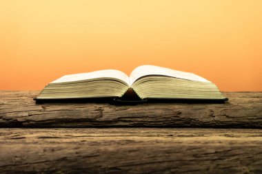 Kutsal İncil'in eski meşe ahşap bir masa üzerine. Güzel turuncu arka plan. Din kavramı.