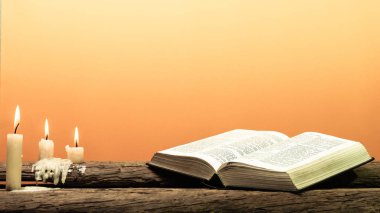 Kutsal İncil'in eski meşe ahşap bir masa üzerine. Güzel turuncu arka plan. Din kavramı.