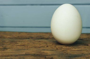 Eski meşe ahşap masa mavi zemin üzerine beyaz yumurta.