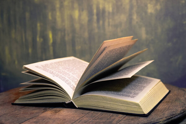 Open old book on a oak wooden table background of school board