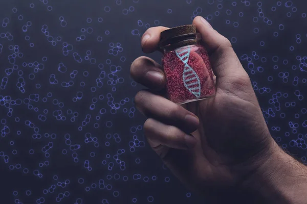 Close up of man holding DNA molecule in Glass bottle. Mixed media.