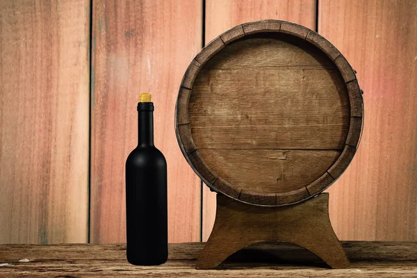 Wooden barrel and black wine bottle on a old oak table of wood.