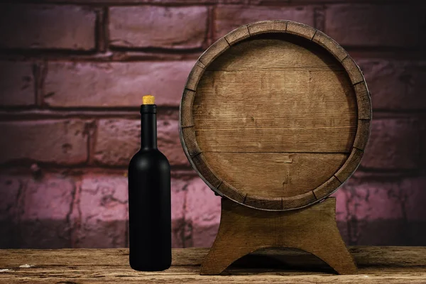 Wooden barrel and black wine bottle on a old oak table of wood.