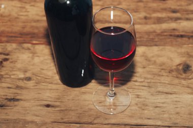 Kırmızı şarap şişesi ve eski ahşap bir masa üzerinde şarap. 