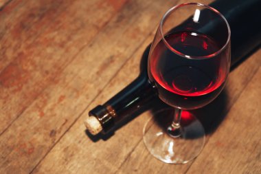 Kırmızı şarap şişesi ve eski ahşap bir masa üzerinde şarap. 