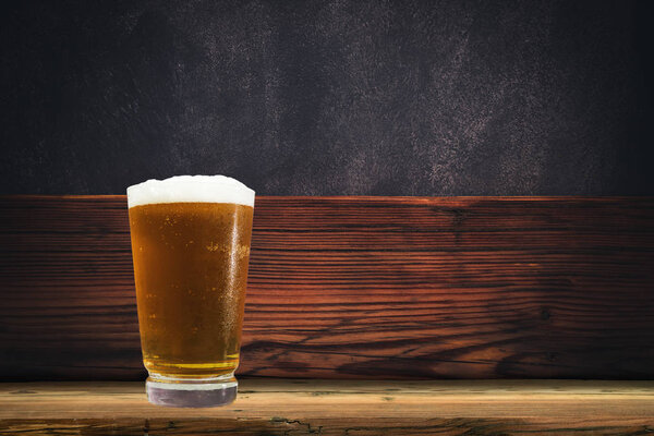 Glass of beer on a old oak table and background