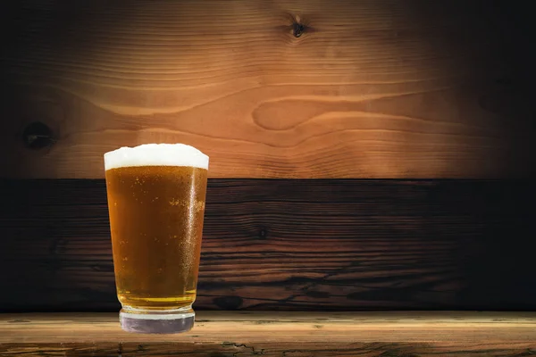 Glass of beer on a old oak table and background
