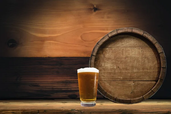 Wooden barrel and glass of beer on a old oak table of wood.