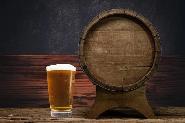 Wooden barrel and glass of beer on a old oak table of wood.