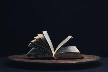 Yuvarlak ahşap bir masa üzerinde bir açık eski kitap. Güzel koyu arka plan