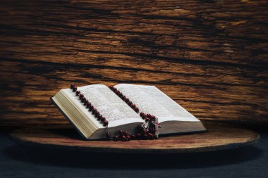 İncil ve eski bir yuvarlak masa üzerinde haç boncuk. Güzel kahverengi meşe ahşap zemin. Din kavramı.