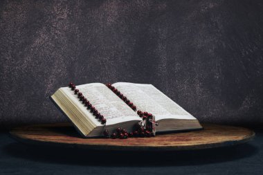 İncil ve eski bir yuvarlak masa üzerinde haç boncuk. Güzel gri duvar arka plan. Din kavramı.