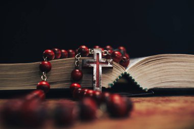 Eski kırmızı boncuk ve İncil'de arka plan üzerinde haç. Makro görünümü.