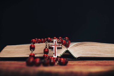 Eski kırmızı boncuk ve İncil'de arka plan üzerinde haç. Makro görünümü.