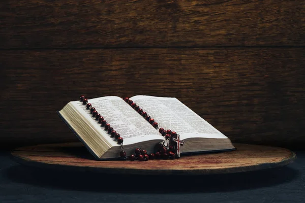 İncil ve eski bir yuvarlak masa üzerinde haç boncuk. Güzel kahverengi ahşap arka plan. Din kavramı.