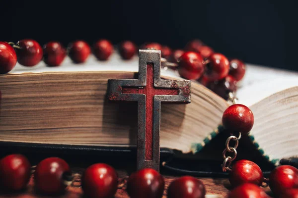 Old red Beads and crucifix on a Holy Bible background. Macro view.
