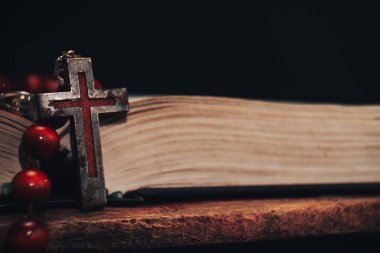 Eski kırmızı boncuk ve İncil'de arka plan üzerinde haç. Makro görünümü.
