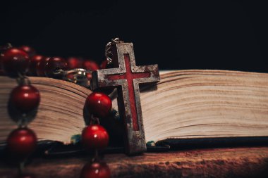 Eski kırmızı boncuk ve İncil'de arka plan üzerinde haç. Makro görünümü.