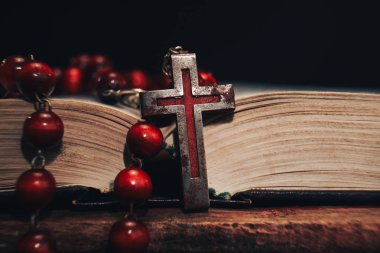 Eski kırmızı boncuk ve İncil'de arka plan üzerinde haç. Makro görünümü.