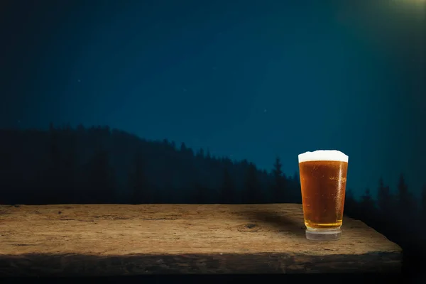Glass of beer on a old oak table and background