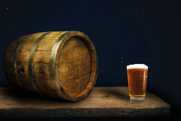 Wooden barrel and glass of beer on a old oak table of wood.