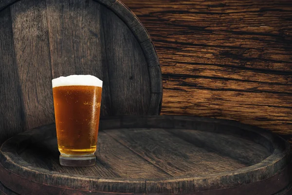 Wooden barrel and glass of beer on a barrel table of wood.