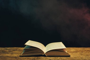 Meşe ahşap bir masa üzerine eski kitap. Arka plan mavi ve kırmızı duman.