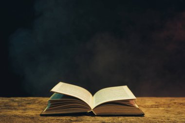 Meşe ahşap bir masa üzerine eski kitap. Arka plan mavi ve kırmızı duman.
