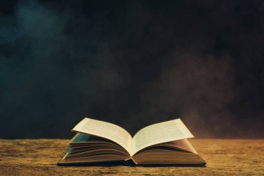 Meşe ahşap bir masa üzerine eski kitap. Arka plan mavi ve kırmızı duman.