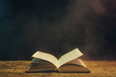 Meşe ahşap bir masa üzerine eski kitap. Arka plan mavi ve kırmızı duman.