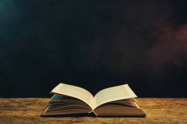 Meşe ahşap bir masa üzerine eski kitap. Arka plan mavi ve kırmızı duman.